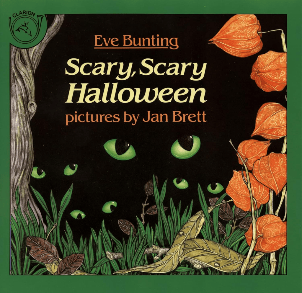 Cover of Scary, Scary Halloween by Eve Bunting and pictures by Jan Brett. Features glowing green eyes in the darkness with grass, a tree trunk, Chinese Lantern plants and fall leaves in the foreground.