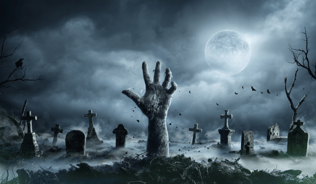 A decaying grayish-blue hand bursts from a dirt mound in a foggy graveyard under a bright full moon. Weathered tombstones and stone crosses rise from the mist. Bats fly across the dark and stormy sky and against gnarled, leafless trees.