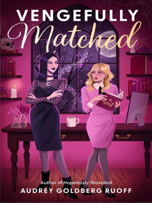 Cover of Vengefully Matched: A Novel by Audrey Goldberg Ruoff, author of Hopelessly Teavoted. Includes a drawing of a tall black haired woman in a black dress facing a shorter blonde woman in a pink dress suit. Behind them is a table with a computer monitor, flowers in beakers, and a mug. Shelves on the wall contain books, candles, and a skull. A large window shows leafless tree branches, a full moon, and a shimmering trail of purple sparkles.
